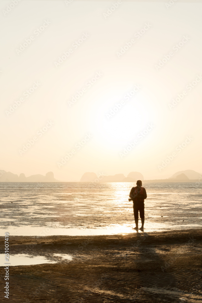 Silhouette of photographer taking picture of landscape during sunset on the beach.