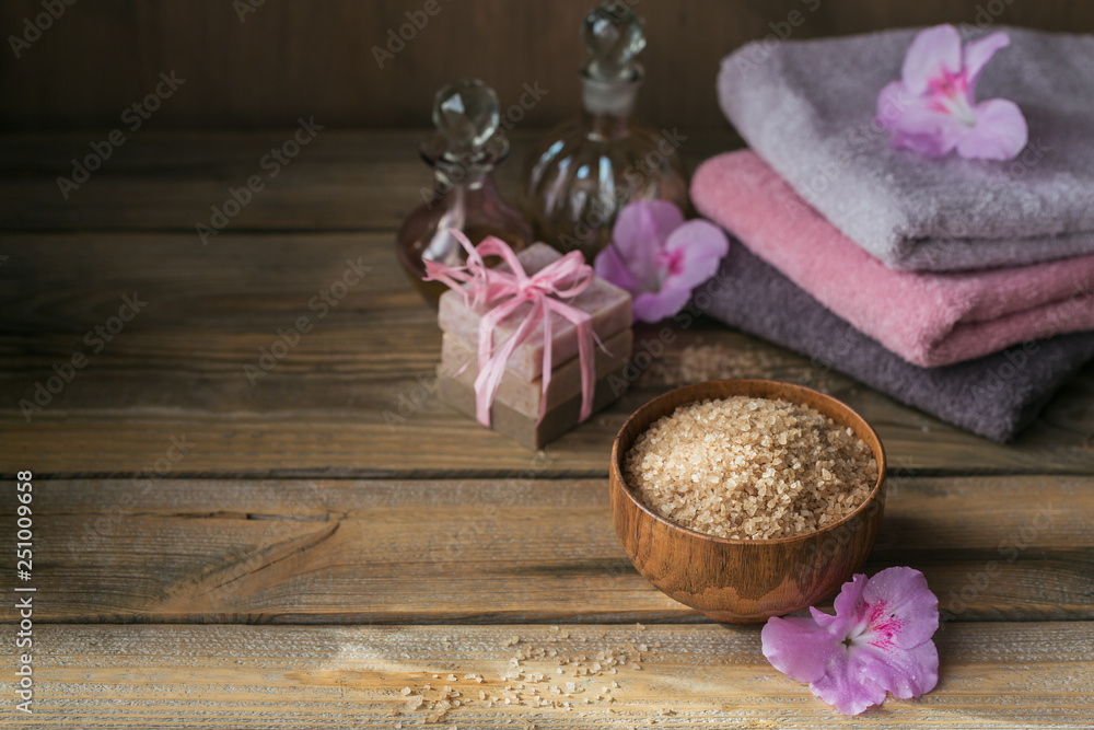 Sea salt, natural handmade soap, natural cosmetic oil and colorful towels with azalea flowers on rustic wooden background Sea salt, natural handmade soap, natural cosmetic oil and colorful towels with azalea flowers on rustic wooden background