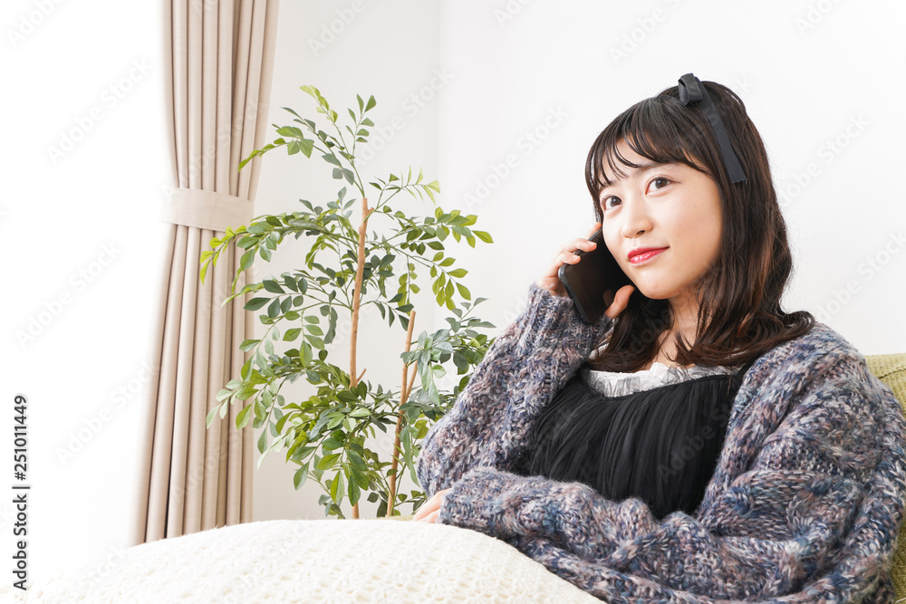 家でスマートフォンを使う若い女性