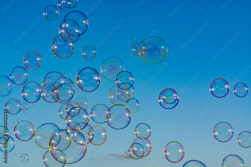Many soap bubbles in air, blue sky, outdoor fun for everybody