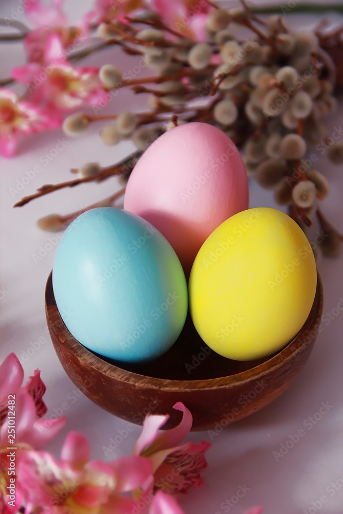 pink yellow blue eggs against a background of willow and flowers for the Easter holiday pink yellow blue eggs against a background of willow and flowers for the Easter holiday