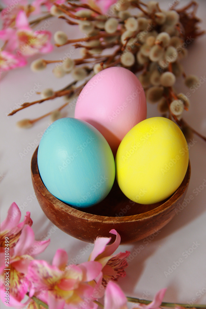 pink yellow blue eggs against a background of willow and flowers for the Easter holiday pink yellow blue eggs against a background of willow and flowers for the Easter holiday