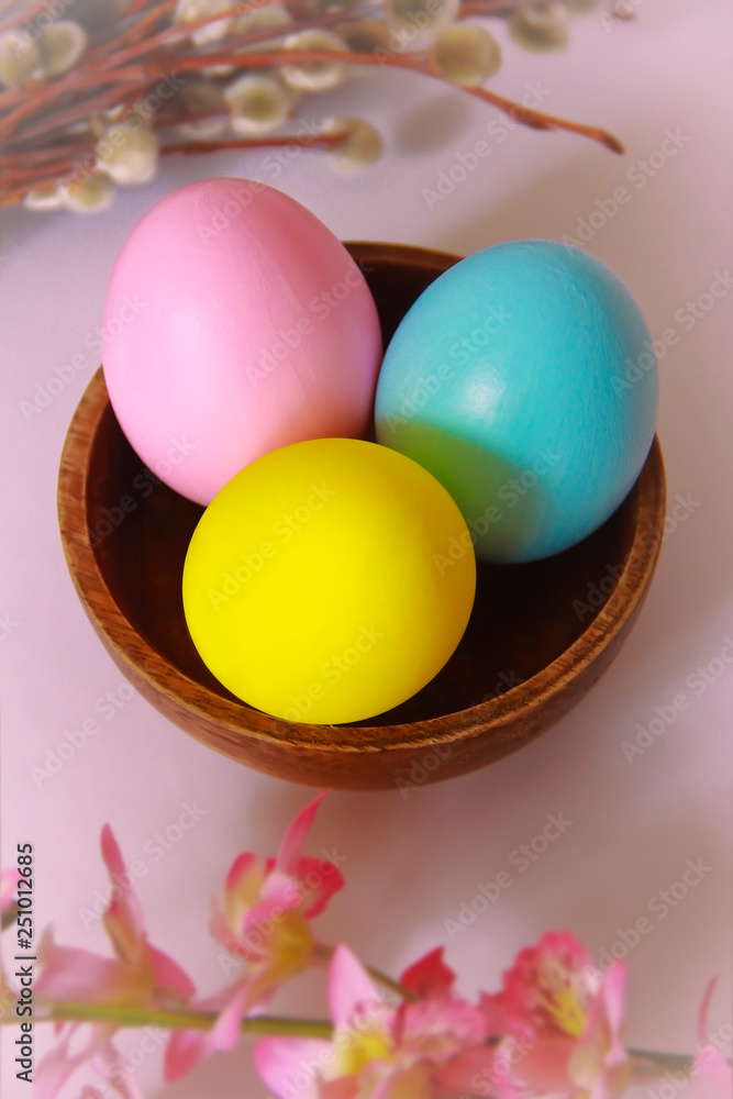 pink yellow blue eggs against a background of willow and flowers for the Easter holiday pink yellow blue eggs against a background of willow and flowers for the Easter holiday