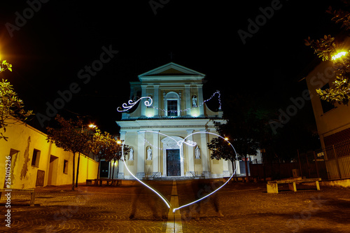 Couple in love makes an heart with light trails in front of Saint Valentine Church, Terni, Umbria, Italia