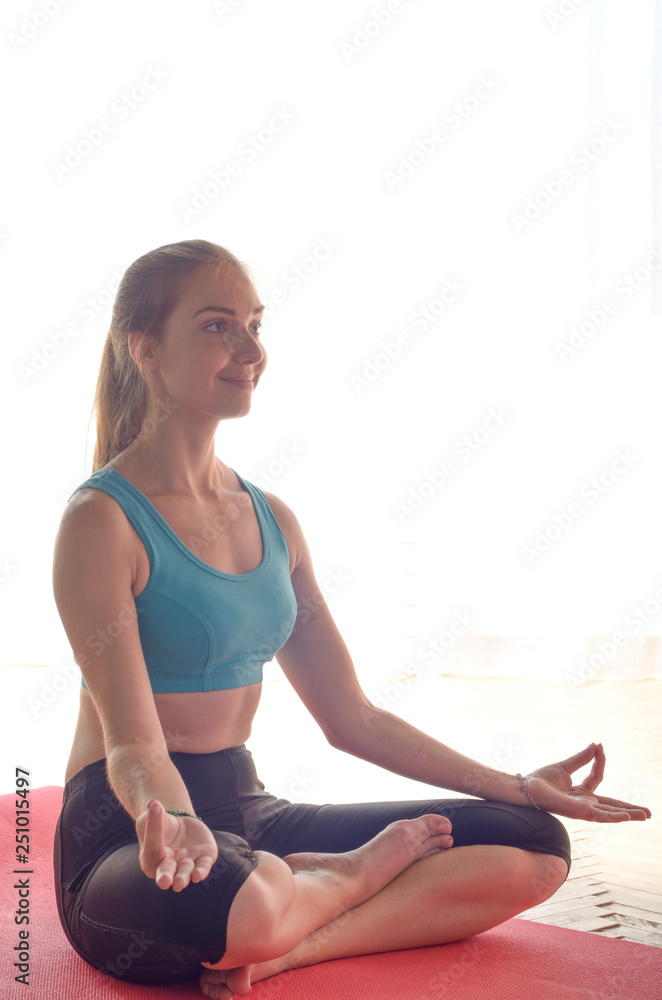 Young happy woman doing yoga sitting meditation at home. Healthy lifestyle concept. Place for text