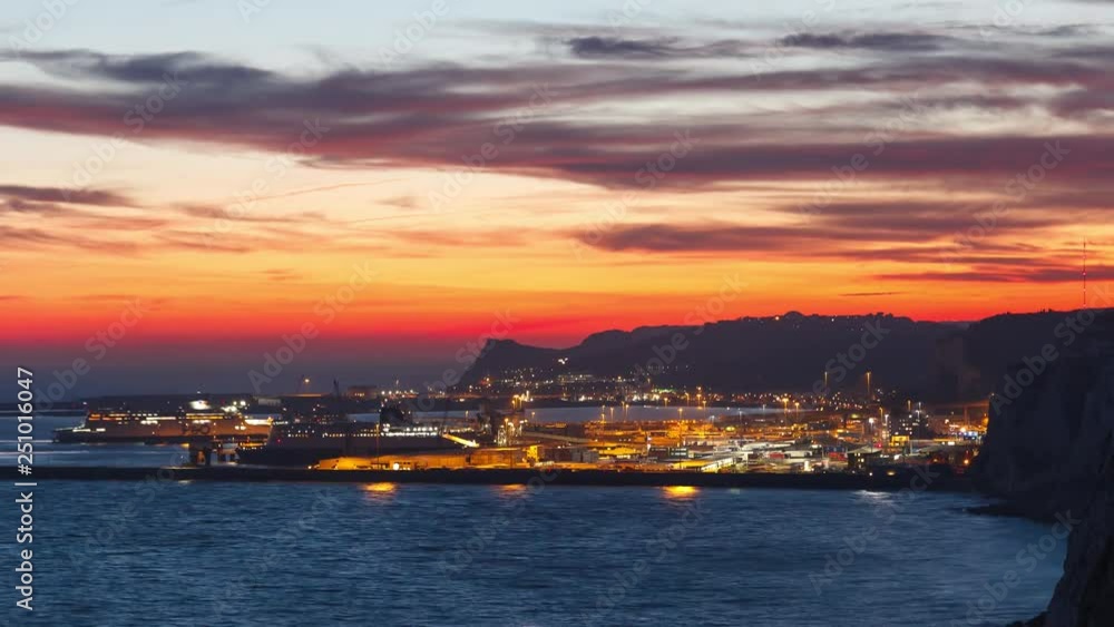 Dover White Cliffs Time-Lapse with the Harbour in the background after sunset. Blue sea and yellow sky with the already lit up harbour with ferries. Dover White Cliffs Time-Lapse with the Harbour in the background after sunset. Blue sea and yellow sky with the already lit up harbour with ferries.