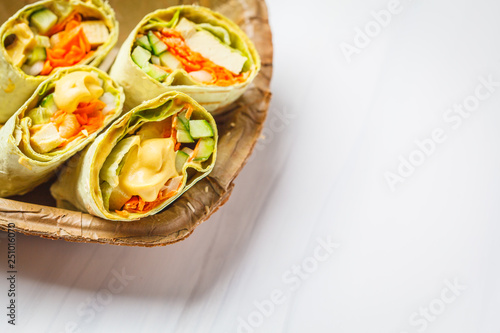 Vegan tofu wraps with cashew cheese sauce and vegetables, white background.