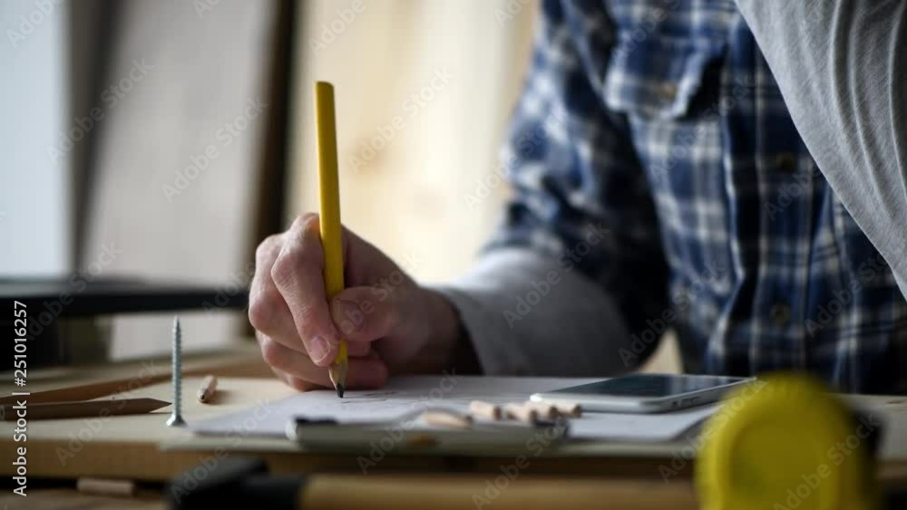 Carpenter sketching pine wood plank for cutting in workshop for small business woodwork project Carpenter sketching pine wood plank for cutting in workshop for small business woodwork project