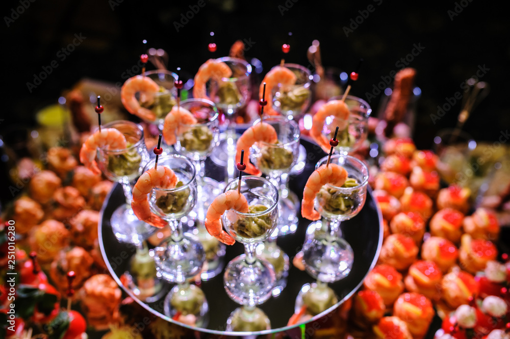 Buffet table with snacks, canapes; shrimp with sauce in glasses at a birthday party