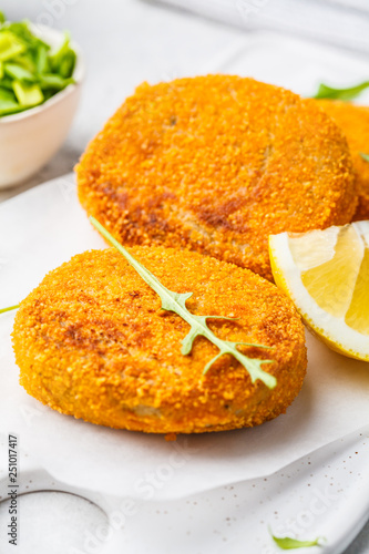 Cooked salmon fish cutlets on white board.
