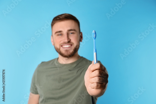 Young man with brush and toothpaste on color background, space for text. Teeth care