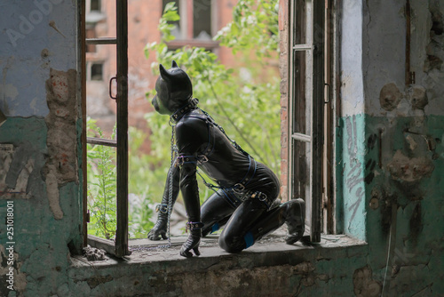 Adult kinky man dressed in fetish latex rubber costume with black mask