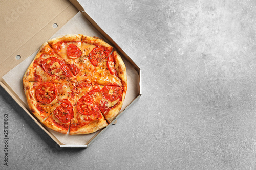 Cheese pizza in carton box on grey background, top view with space for text. Food delivery service
