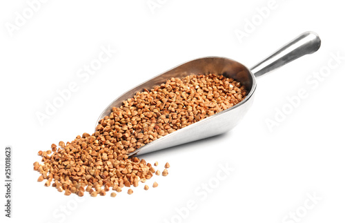 Scoop with uncooked buckwheat on white background
