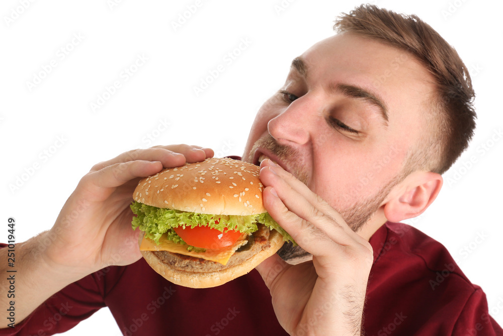 Young man eating tasty burger on white background