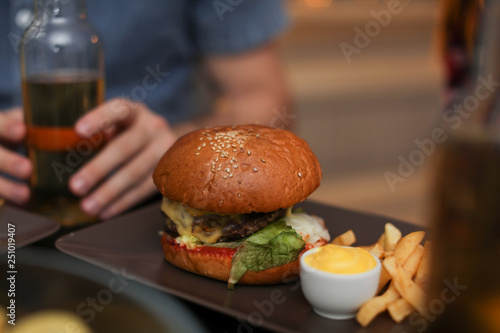 Tasty burger with French fries served on table in cafe