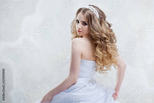 Charming young bride with luxury hairstyle. Beautiful woman in wedding dress. Hairstyle with fluffy curls.