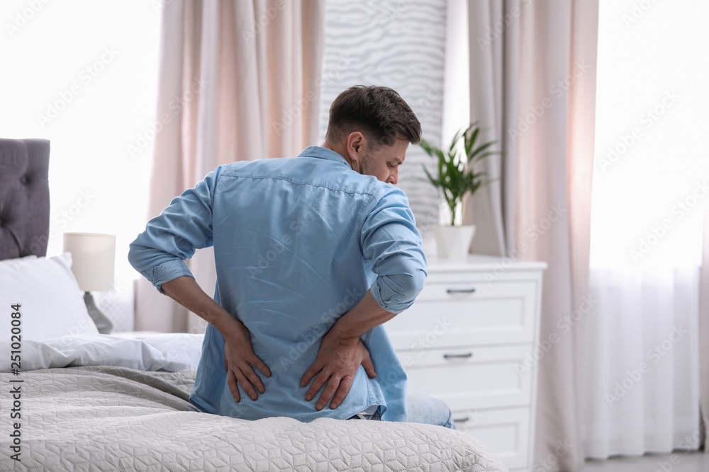 Young man suffering from back pain at home Young man suffering from back pain at home