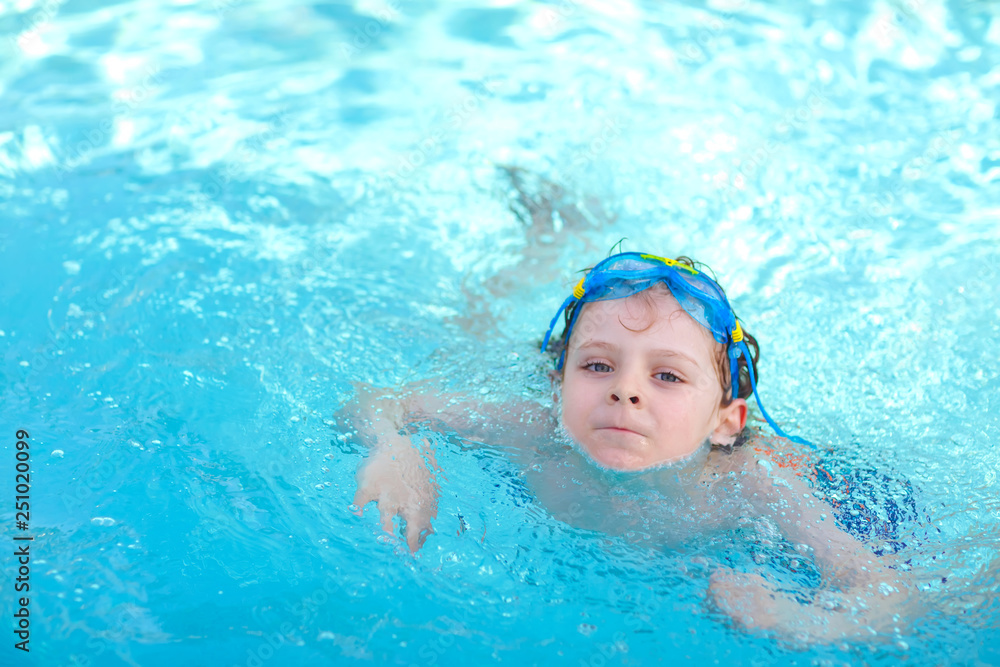 little preschool kid boy making swim competition sport. Kid with swimming goggles reaching edge of the pool . Child having fun in an swimming pool. Active happy child winning. sports, active leisure.