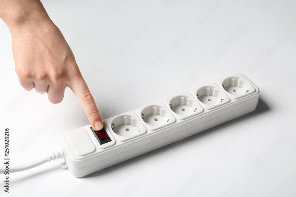 Woman pressing power button of extension cord on white background, closeup. Electrician's equipment Woman pressing power button of extension cord on white background, closeup. Electrician's equipment