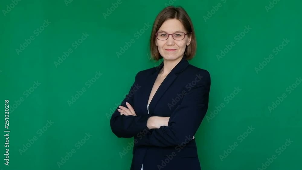 Confident business woman with crossed arms looking at camera and smiling on green background. Chroma key. Close up Confident business woman with crossed arms looking at camera and smiling on green background. Chroma key. Close up