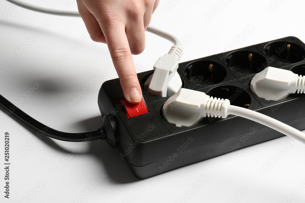 Woman pressing power button of extension cord on white background, closeup. Electrician's equipment Woman pressing power button of extension cord on white background, closeup. Electrician's equipment