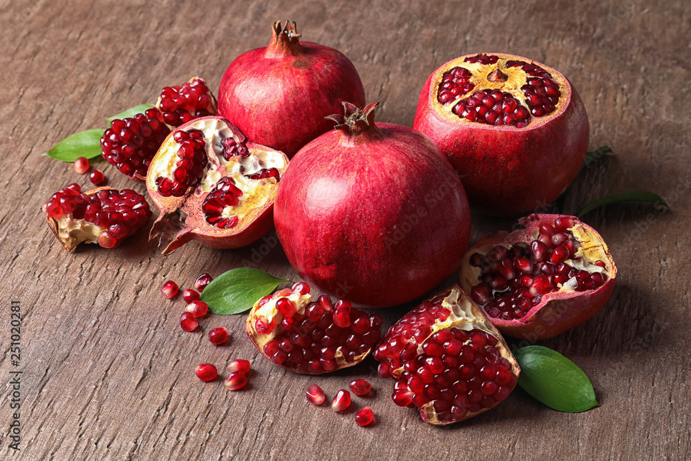 Composition with ripe pomegranates and leaves on color background Composition with ripe pomegranates and leaves on color background