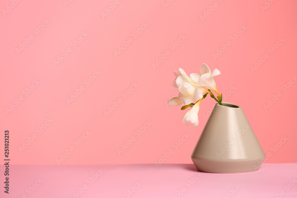Stylish vase with beautiful flower on table against color background, space for text Stylish vase with beautiful flower on table against color background, space for text