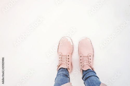 Female legs in pink boots in the snow