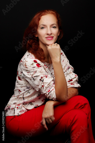 Red-haired young woman in the studio on a black background.
