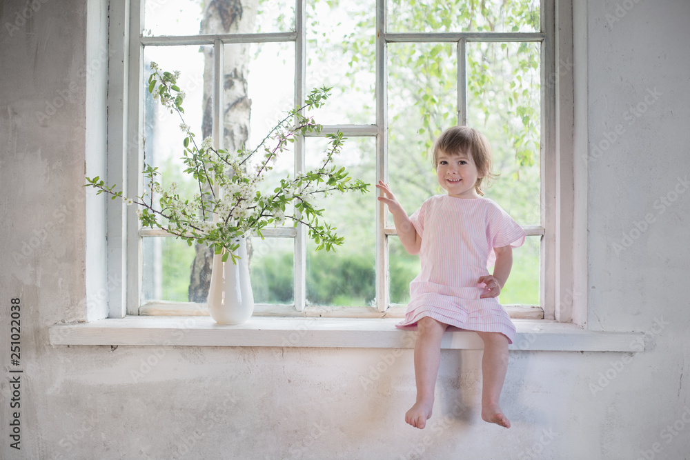 beautiful little girl on old windowsill with spring flowers beautiful little girl on old windowsill with spring flowers