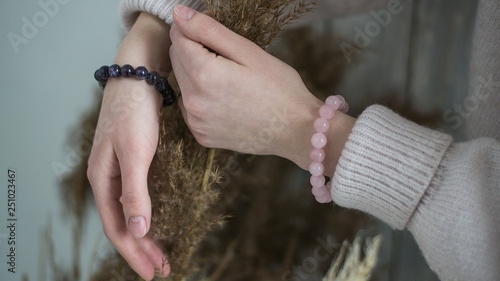 Photographie bracelets of purple and pink stones on the hand, in the hands of dried flowers,