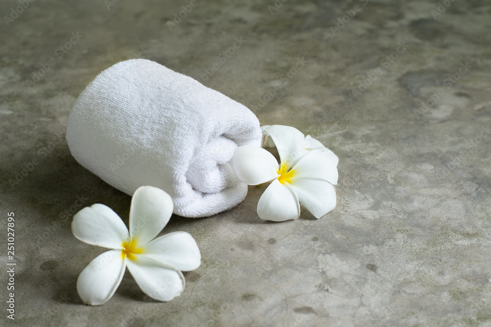 spa towel with plumeria on the grey stone table. spa towel with plumeria on the grey stone table.