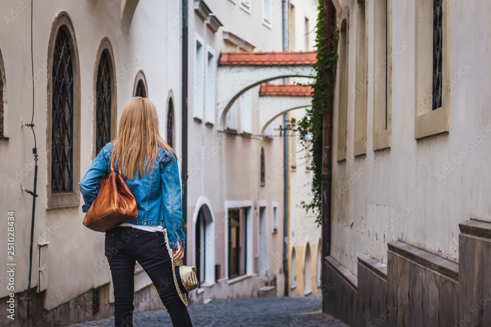 Tourist woman wearing jeans jacket is walking in ancient city Olomouc, Czech Republic. Tourism in Europe