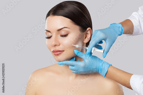 The doctor cosmetologist makes the Rejuvenating facial injections procedure for tightening and smoothing wrinkles on the face skin of a beautiful, young woman in a beauty salon.Cosmetology skin care. photo