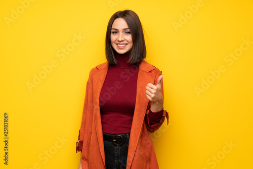 Young woman with coat giving a thumbs up gesture and smiling © luismolinero