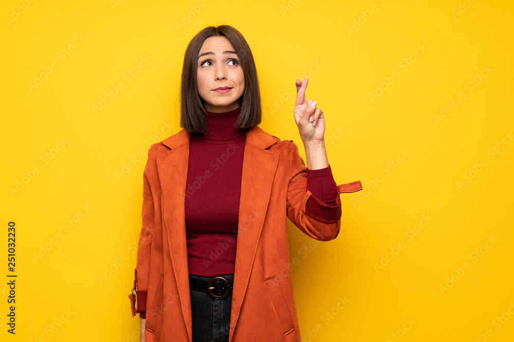 Young woman with coat with fingers crossing and wishing the best Young woman with coat with fingers crossing and wishing the best