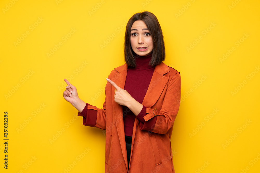 Young woman with coat frightened and pointing to the side