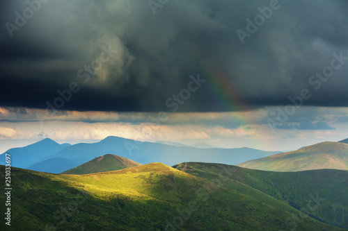 Summer in the Carpathian massif of Swidovets, located in Ukraine, with a lot of lakes, green pasture for sheep and horses, and wonderful, after a stormy sky with a rainbow.