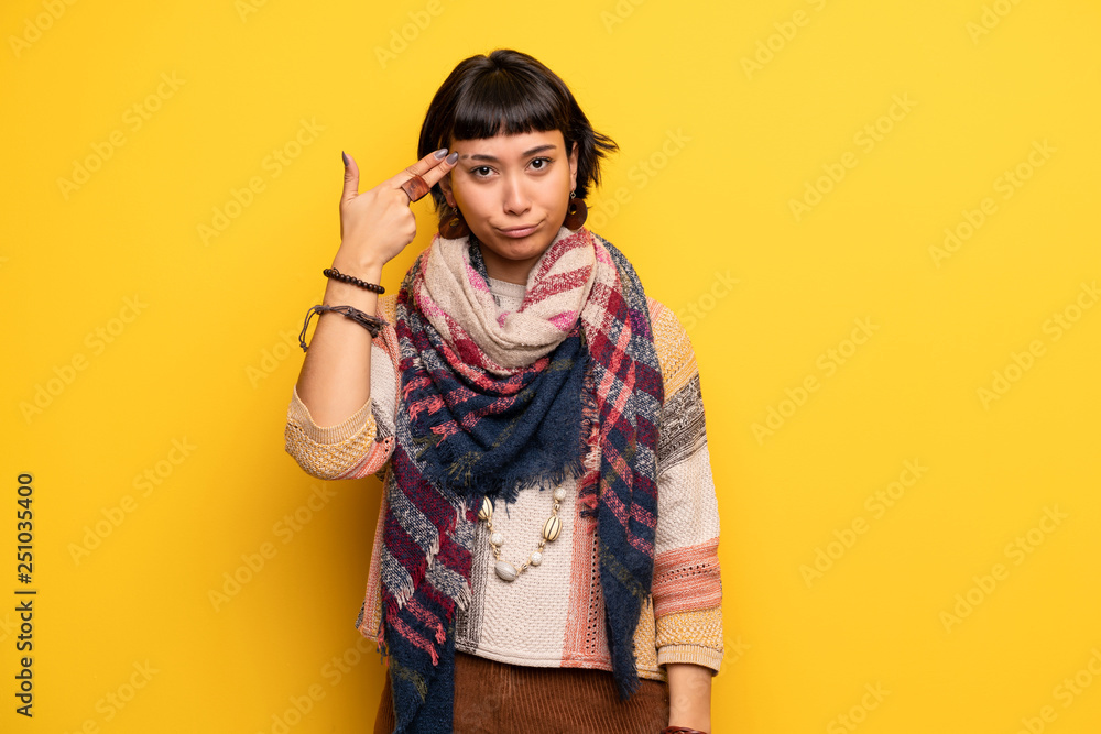 Young hippie woman over yellow wall with problems making suicide gesture Young hippie woman over yellow wall with problems making suicide gesture