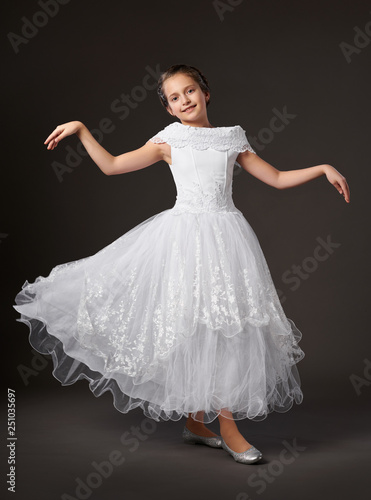 little girl is dancing in a white ball gown, dark background