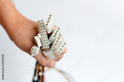 hand holds power cables from power supply unit on white background, PC motherboard power cables and connectors, 4pin peripheral connector, ATX 20+4 pin photo