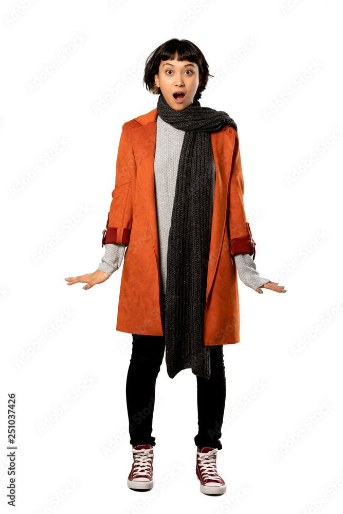 A full-length shot of a Short hair woman with coat surprised and shocked while looking right over isolated white background