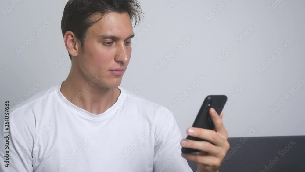 Attractive smiling man using smartphone sending message on social media and drinking coffee indoor Attractive smiling man using smartphone sending message on social media and drinking coffee indoor