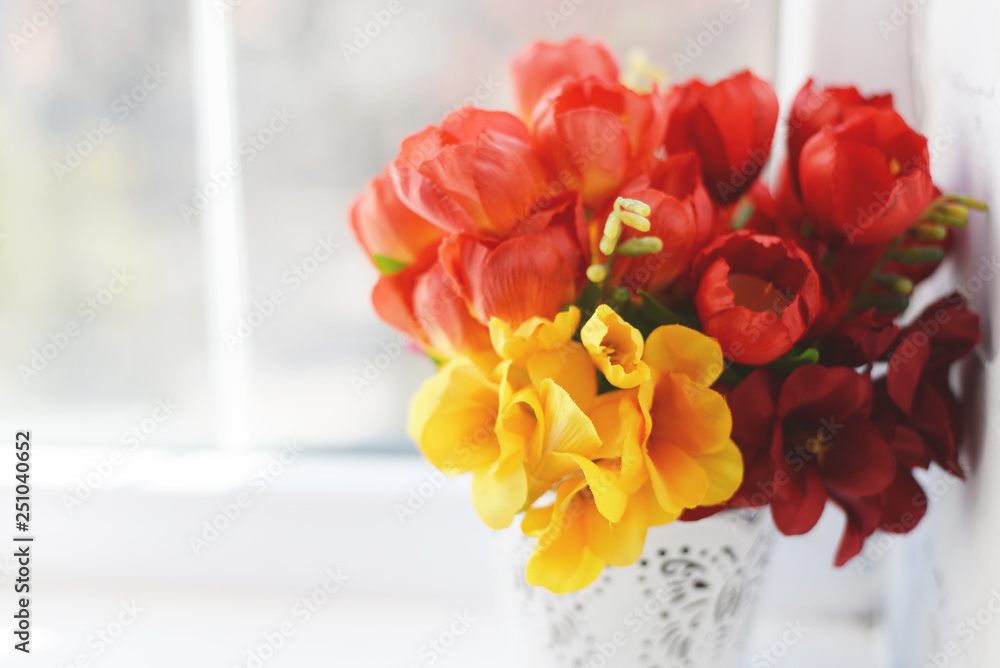 Flower arrangement with tulips and ranunculus on a white wooden floor. Spring flower arrangement in a vase