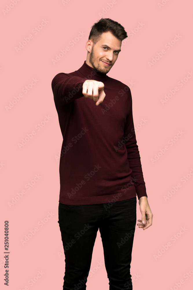 Fototapeta premium Man with turtleneck sweater points finger at you with a confident expression over pink background