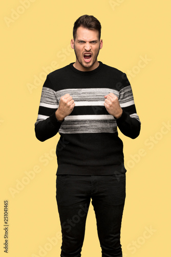 Handsome man frustrated by a bad situation over yellow background