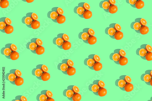 Fototapeta Naklejka Na Ścianę i Meble -  Oranges on a bright colored green background. Repeating pattern, preparation for wallpaper citrus mood.