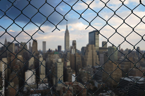 View on the New York city through the hole of steel mesh wire fence. Concept