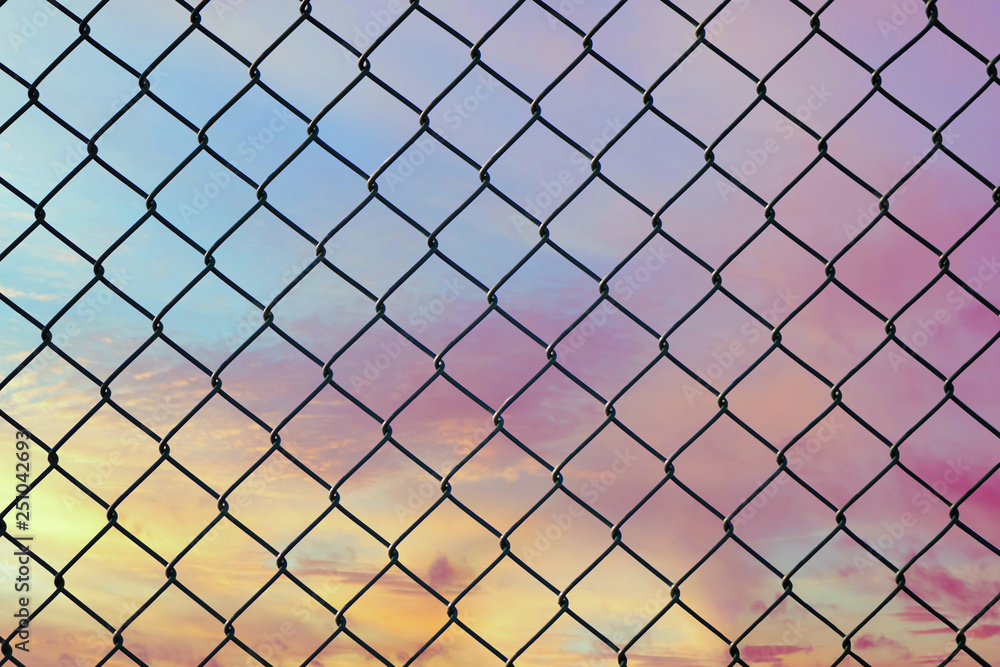 Conceptual image of twilight sky with effect of light pastel tone and steel mesh wire fence. Concept of hope and freedom Conceptual image of twilight sky with effect of light pastel tone and steel mesh wire fence. Concept of hope and freedom